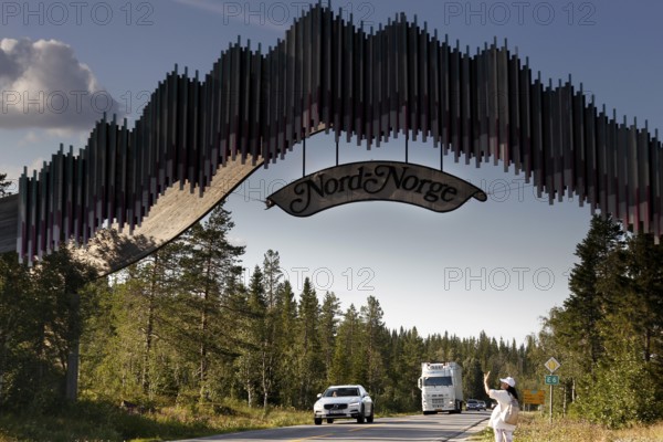 Distinctive wooden archway across the road with passing cars, zero