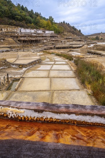 Traditional salt evaporation ponds creating white salt crystals and saline water, showcasing the