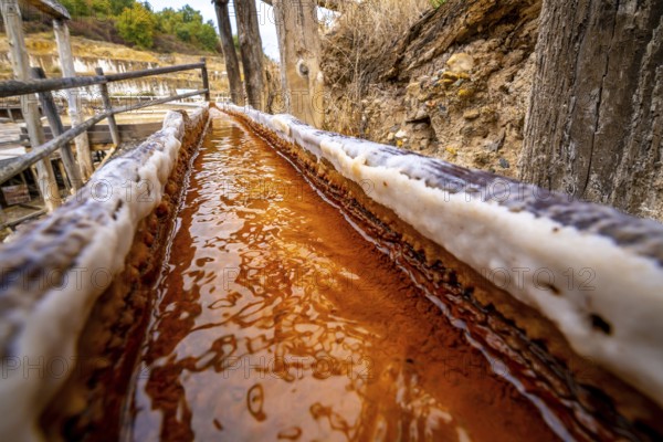 Brine rich in iron and minerals flows through a wooden channel at the ancient salt flats of anana