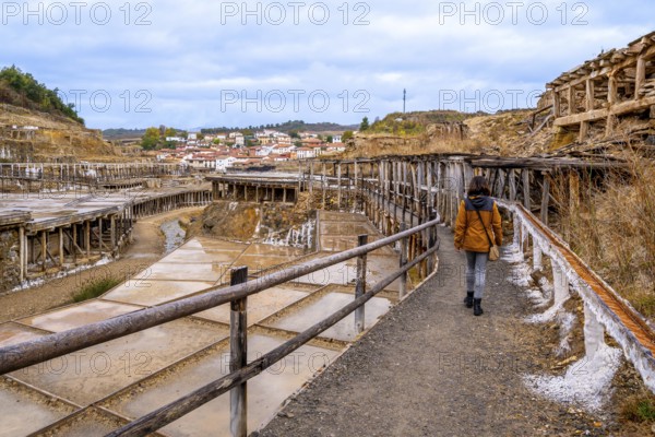 Woman walking along a path next to the historic terraced salt evaporation ponds of the salt valley,