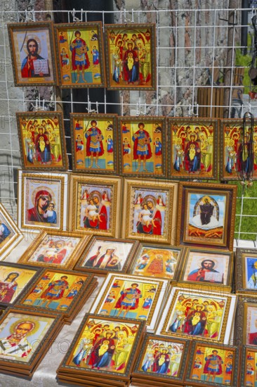 Icons in various frames with bright colors depict religious figures at a market stand, stand in