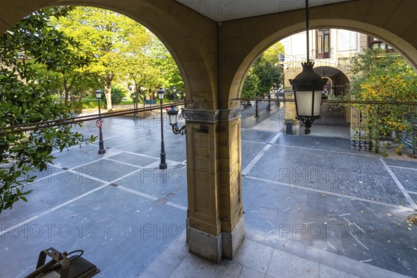 Arched arcade entrance providing a view through to gipuzkoa square park in san sebastian, featuring