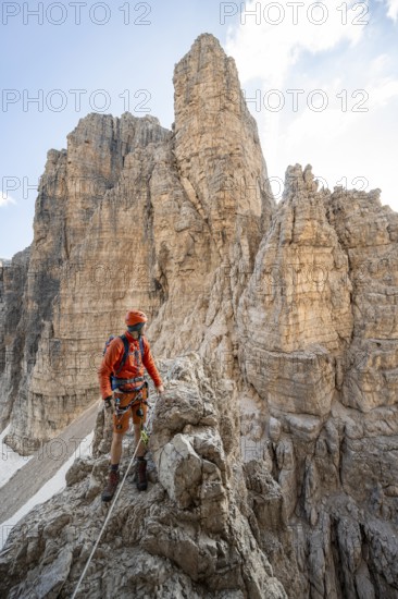 Mountaineer climbs on an exposed rock in the secured Via Ferrata Bocciere Centrale via ferrata,