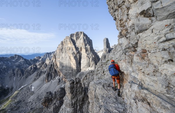 Mountaineer climbs an exposed rock band in the secured Via Ferrata Bocciere Centrale via ferrata,