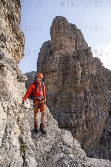 Mountaineer climbs an exposed rock band in the secured Via Ferrata Bocciere Centrale via ferrata,