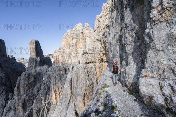Mountaineers on an exposed rock band in the secured Via Ferrata Bocciere Centrale via ferrata,