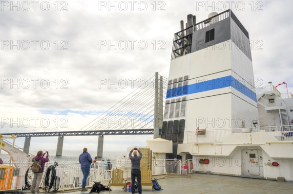 Passengers on a ship with a view of the Øresund Bridge, a ferry under a massive bridge structure of