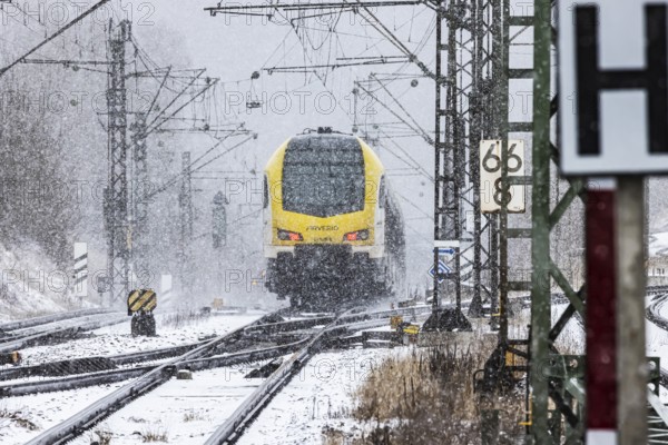 Regional train from Arverio on its way through a winter landscape in snowfall. The railcar train is