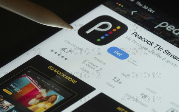 Dhaka, Bangladesh- 30 Oct 2025: Peacock TV app on a iPad screen with a pen pointing at the install