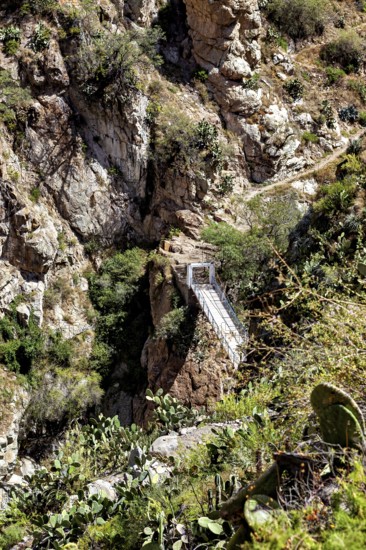 Suspension bridge that crosses a deep gorge between rocks, The landscape of the Colca Canyon in the