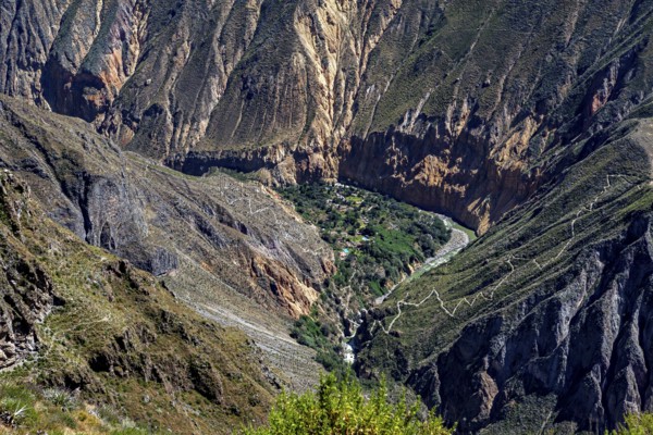 Dramatic gorge with lush greenery in the valley floor surrounded by steep cliffs and hiking trails,