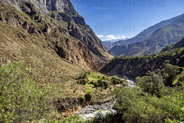 Wide valley with green vegetation and river, surrounded by imposing mountains, the landscape of the