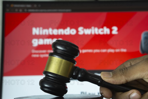 Dhaka, Bangladesh- 20 June 2025: A hand holds a gavel in front of a computer screen displaying