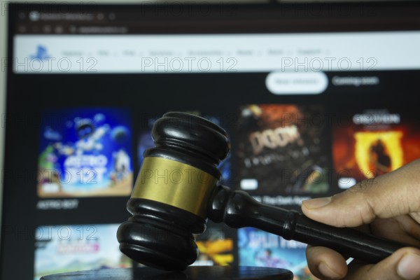 Dhaka, Bangladesh- 20 June 2025: A hand holds a gavel in front of a computer screen displaying