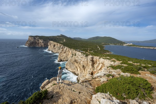 Tourist enjoying the view of steep cliffs by the sea, coastal landscape, cliffs on the Capo Caccia