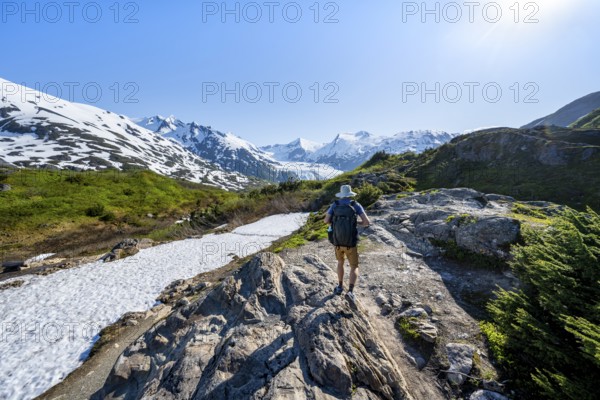 Hikers on the Portage Pass Trail, snow-covered mountains and Portage Glacier glaciers, near