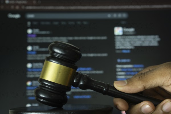 Dhaka, Bangladesh- 20 June 2025: A hand holds a gavel in front of a computer screen displaying