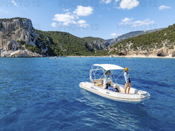 Motor boat off picturesque rocky coast, cliffs and Cala Luna beach, aerial view, Golfo di Orosei,