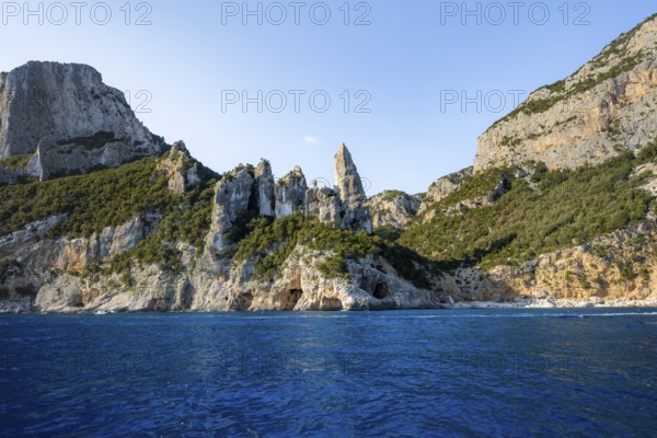 Picturesque rocky coast, cliffs with caves in the morning light, L'Aguglia rock peak, blue sea and