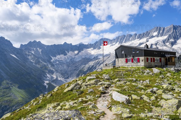 Mountain hut Bergseehütte with Swiss flag in picturesque mountain landscape, view of Damma Glacier