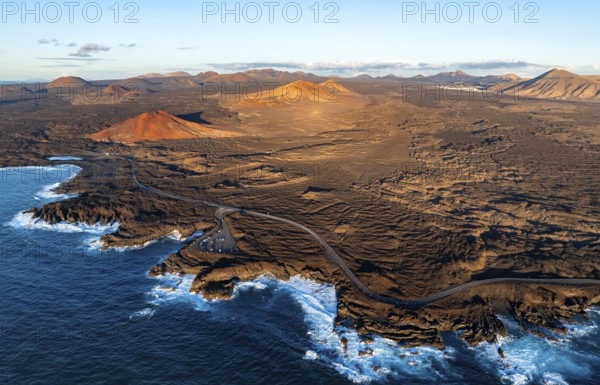 Coast with lava fields, volcanic landscape near Los Hervideros with red volcano Montaña Bermeja, in