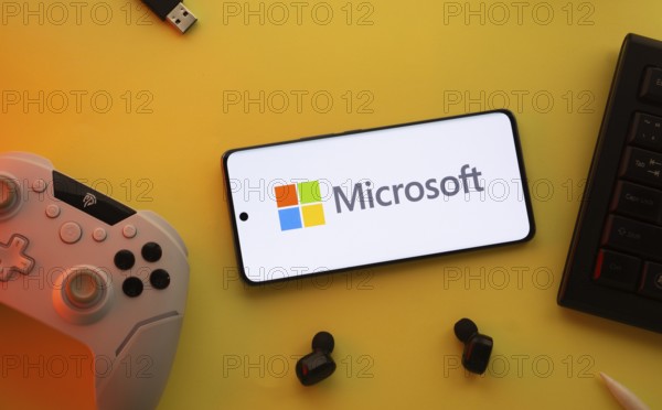 Dhaka, Bangladesh- 23 Mar 2025: Smartphone with Microsoft logo, game controller, and earbuds on a