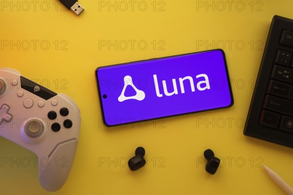 Dhaka, Bangladesh- 23 Mar 2025: Smartphone with Amazon Luna logo, game controller, and earbuds on a