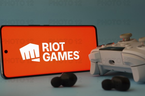 Dhaka, Bangladesh- 23 Mar 2025: A smartphone with a Riot games icon next to a controller and