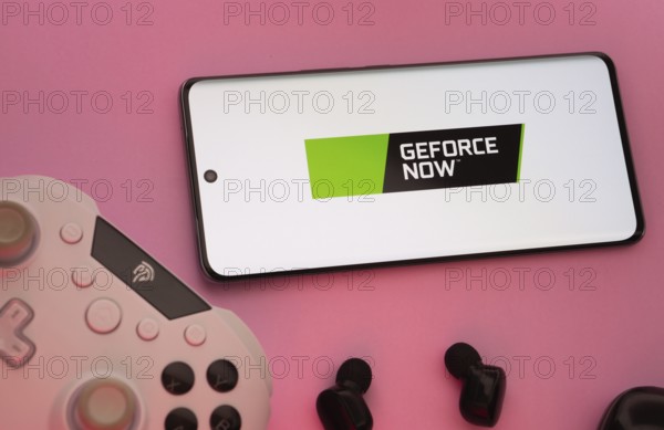 Dhaka, Bangladesh- 22 Mar 2025: Smartphone with Geforce Now logo, game controller, and earbuds on a