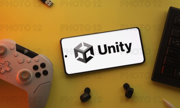 Dhaka, Bangladesh- 23 Mar 2025: Smartphone with Unity logo, game controller, and earbuds on a