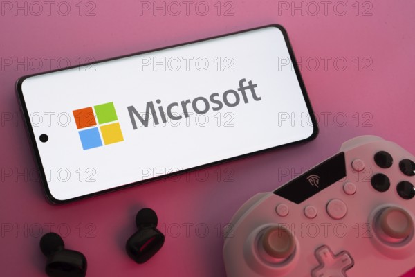 Dhaka, Bangladesh- 22 Mar 2025: Smartphone with Microsoft logo, game controller, and earbuds on a