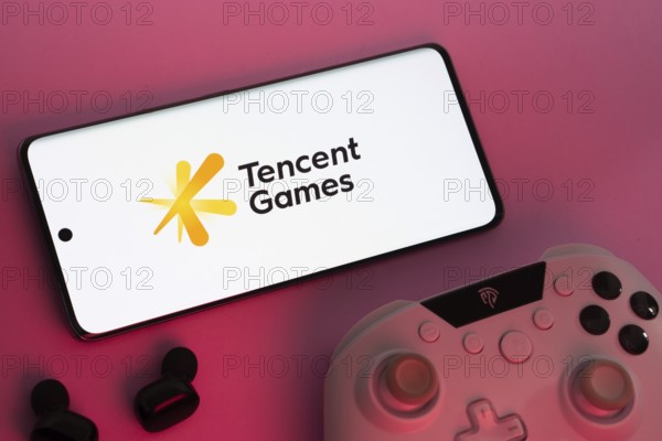 Dhaka, Bangladesh- 22 Mar 2025: Smartphone with Tencent Games logo, game controller, and earbuds on