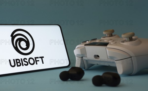 Dhaka, Bangladesh- 23 Mar 2025: A smartphone with a Ubisoft icon next to a controller and earbuds