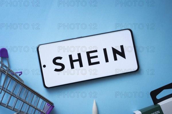 Dhaka, Bangladesh- 03 July 2025: Smartphone displaying SHEIN logo with shopping cart on a blue