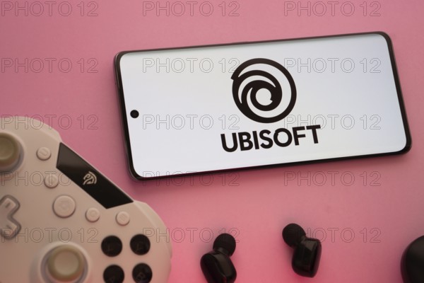 Dhaka, Bangladesh- 22 Mar 2025: Smartphone with Ubisoft logo, game controller, and earbuds on a