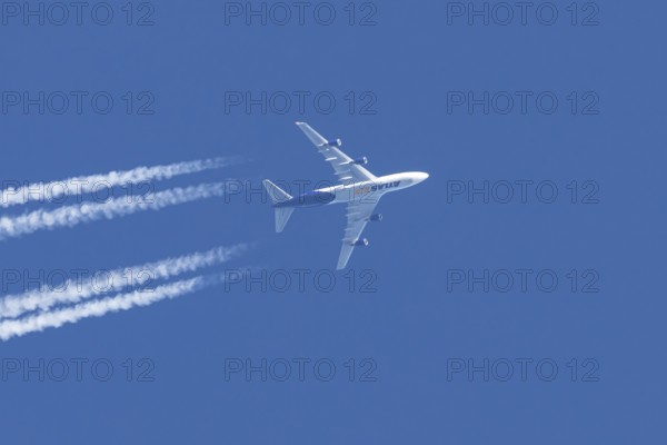 Boeing 747 jumbo jet cargo aircraft of Atlas air airlines flying in a blue sky with contrails or