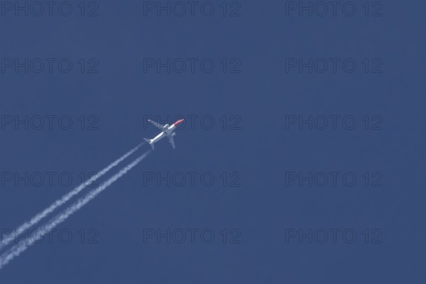 Boeing 737 jet passenger aircraft of Norwegian Air airlines flying in a blue sky with contrails or