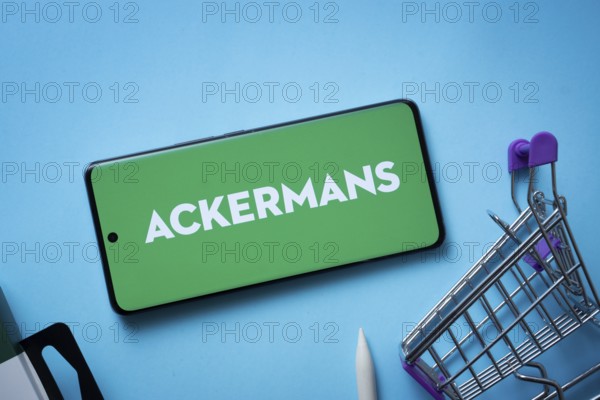 Dhaka, Bangladesh- 03 July 2025: Smartphone displaying Ackermans logo with shopping cart on a blue
