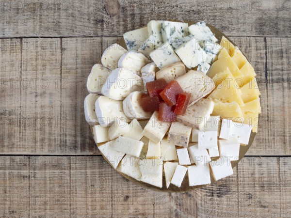 Top view assorted cheese platter with fruit paste on wooden background