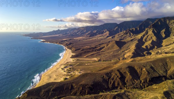 Desert landscape converges with ocean along a rugged coastal area, shore break at cliffs, blue