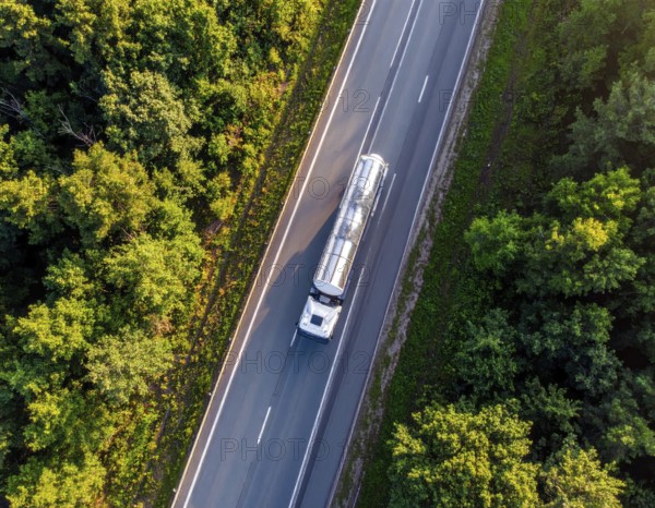 Petrol cargo truck lorry tanker driving on highway hauling oil products at sunrise, wide hilly