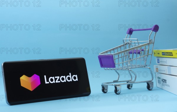 Dhaka, Bangladesh- 03 July 2025: Smartphone with Lazada logo next to a small shopping cart and
