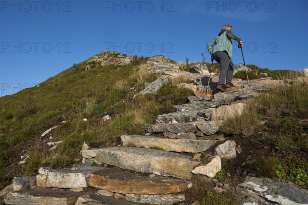 Woman with hiking poles walking up Rørsethornet stone stairs, with 3292 steps one of the longest