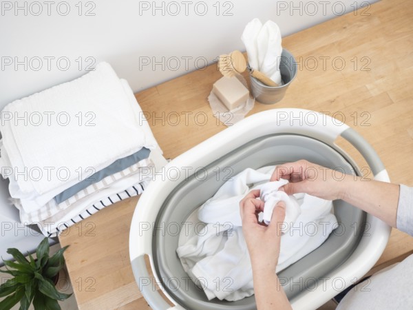 Woman inspecting clothes for stains before washing, preparing laundry in a sustainable way with