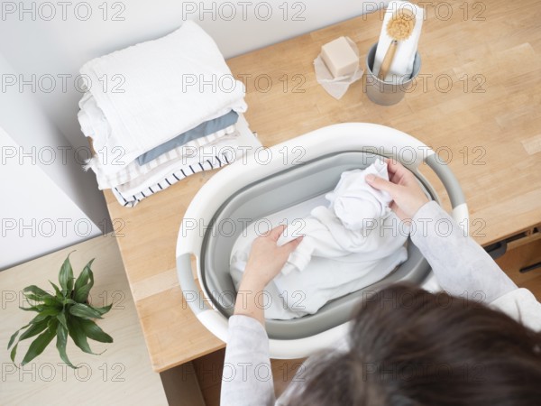 Housewife putting white clothes into a basin preparing laundry washing using natural soap bar and