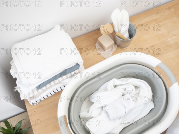 Eco-friendly laundry preparation featuring natural soap, brush, and folded clothes on a wooden