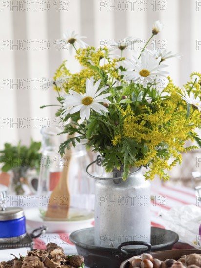 White daisies and yellow goldenrod create a vibrant centerpiece in a rustic milk can, adding a