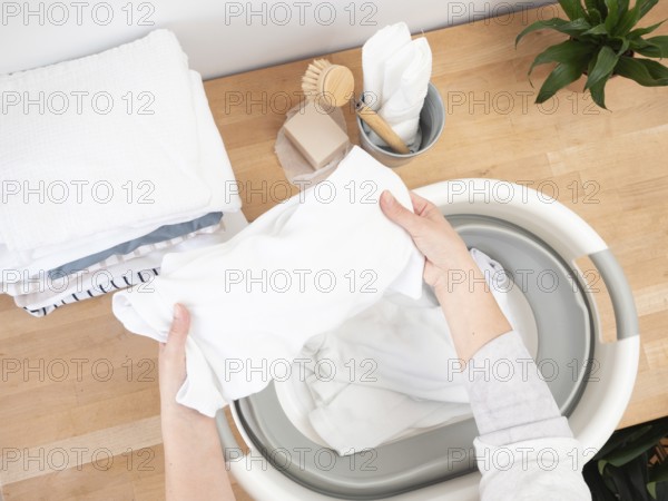 Housewife putting white clothes into basin, doing laundry chores at home