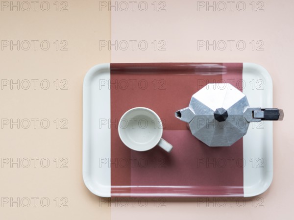 Overhead view of a moka pot and an empty coffee cup sitting on a serving tray, arranged on a