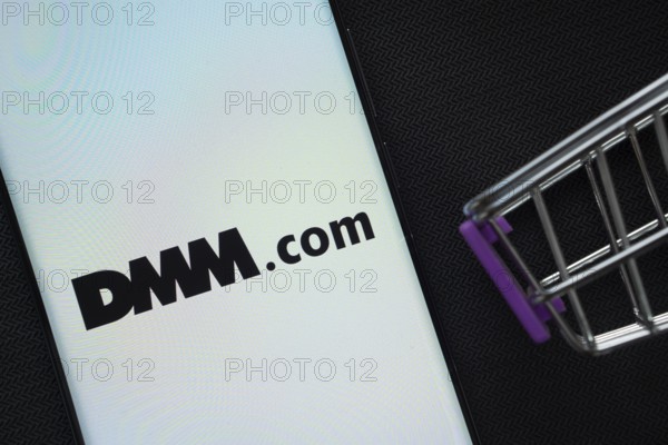 Dhaka, Bangladesh- 03 Oct 2025: A smartphone displaying the Dmm.com logo next to a miniature